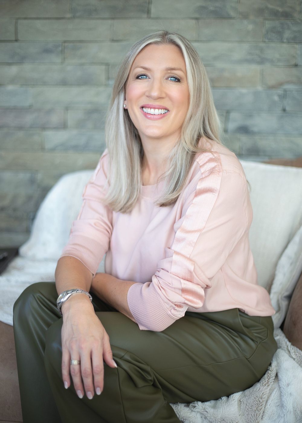 Professional lifestyle portrait series showing a person in a pink top and olive pants relaxing on a light gray couch.