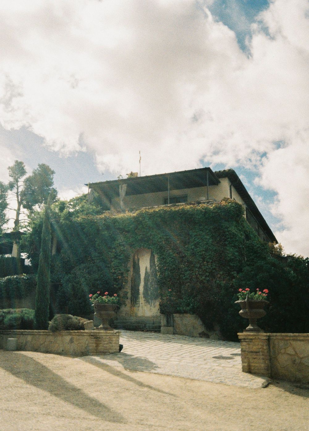 Panoramic view of a rustic stone building on a hillside under cloudy skies.