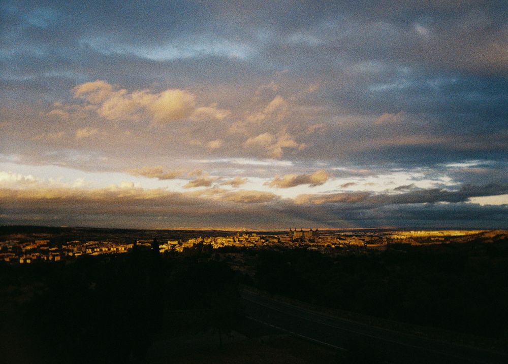 Dramatic sunset sky with golden clouds illuminating a vast valley landscape below.
