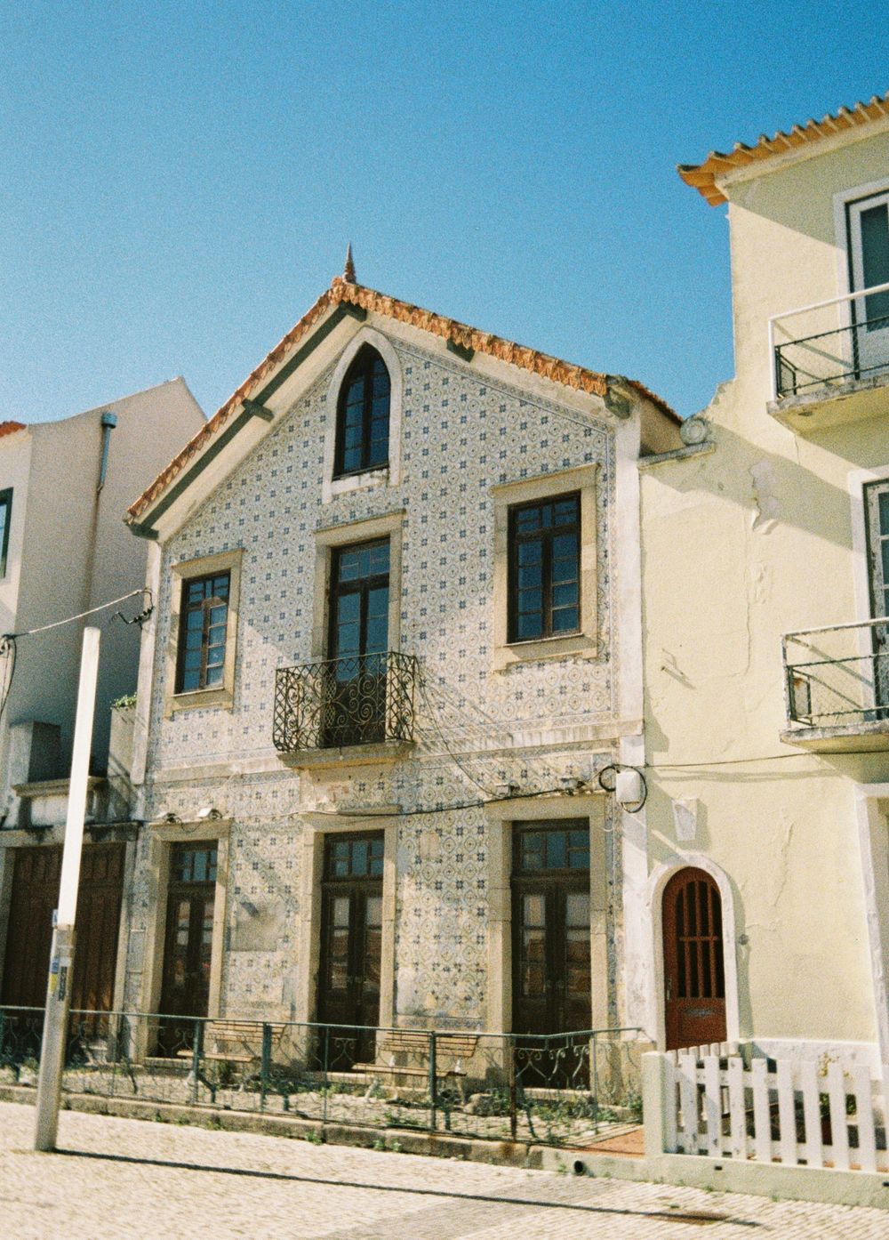 Traditional Portuguese house with decorative tile facade and ornate balcony in white and blue tones.