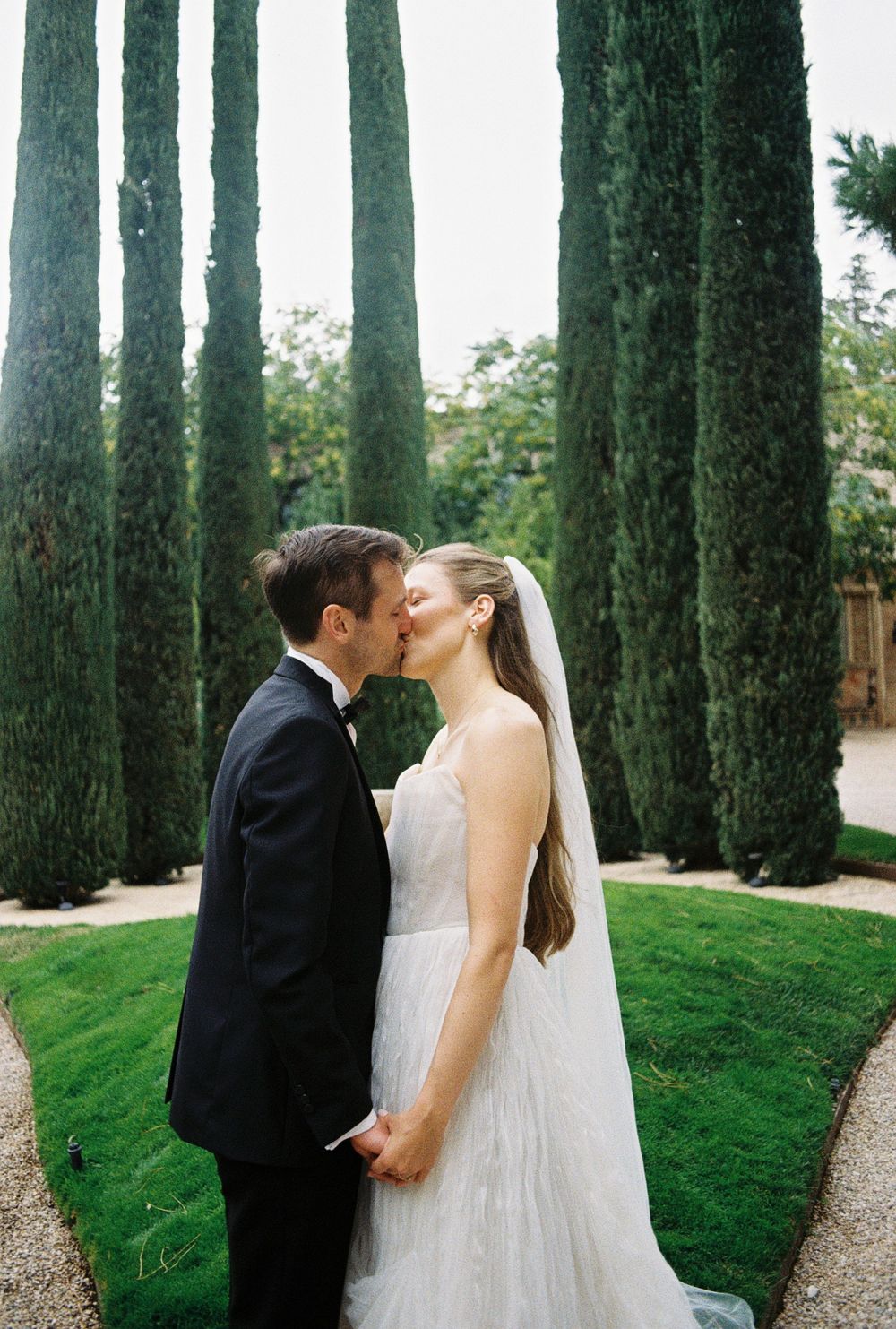 A romantic scene with cypress trees creating a dramatic backdrop in a manicured garden setting.