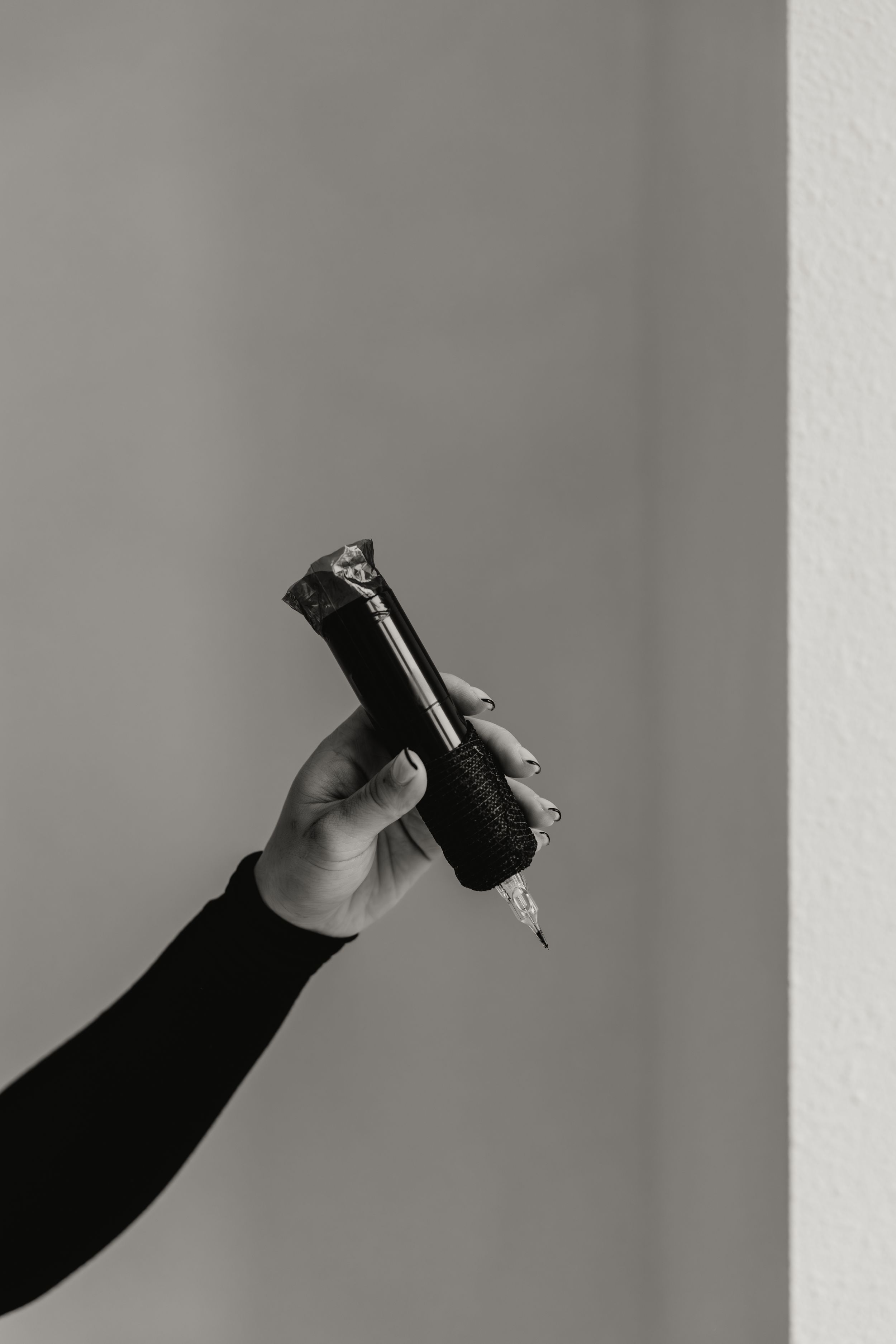 A black and white sequence of images showing a hand holding and pouring a small bottle against a gray background.