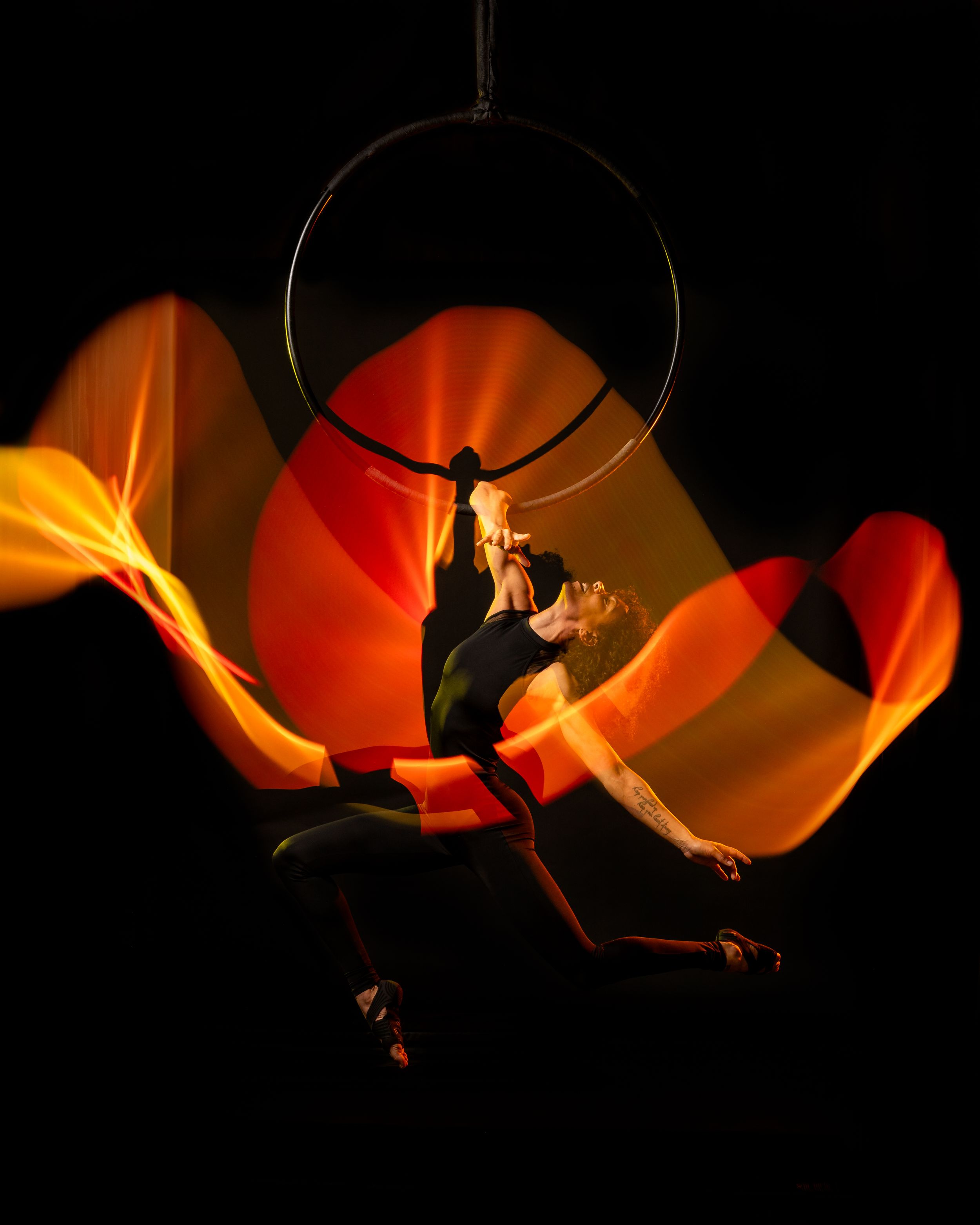 Fire Ombre, Aerialist silhouette outlined by bright light painting; polished aerial arts photo capturing motion, color, and clean lines.