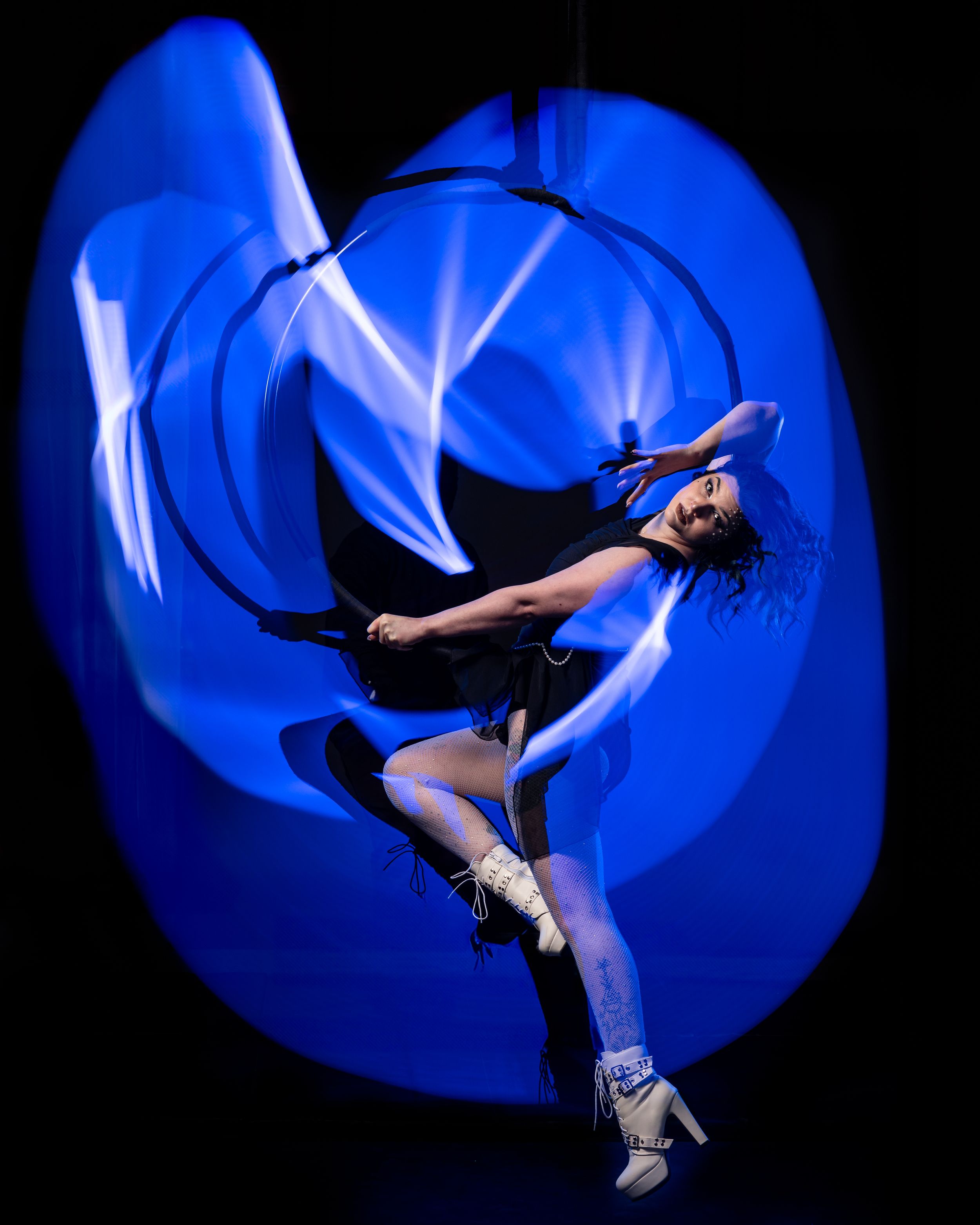 Blue, Aerialist silhouette outlined by bright light painting; polished aerial arts photo capturing motion, color, and clean lines.