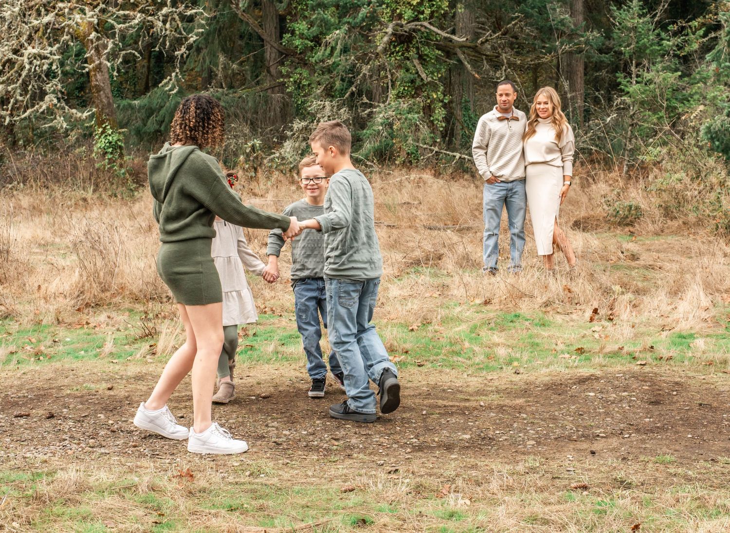 A group of people walking and playing outdoors on a dirt path through a wooded area.