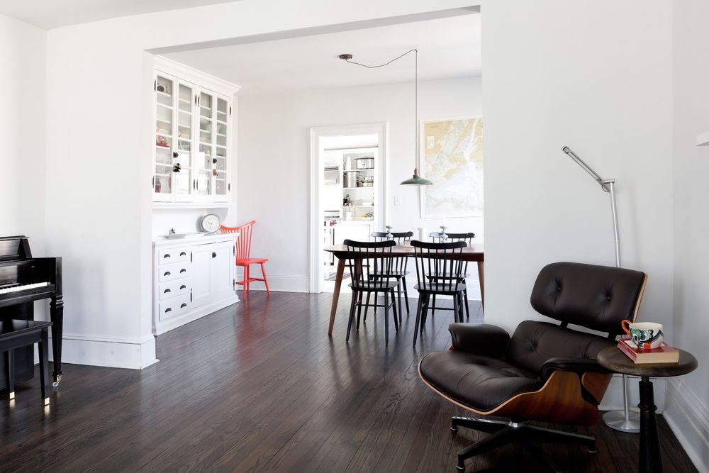 Modern open concept living space with dark hardwood floors, Eames lounge chair, and white built-in cabinetry.