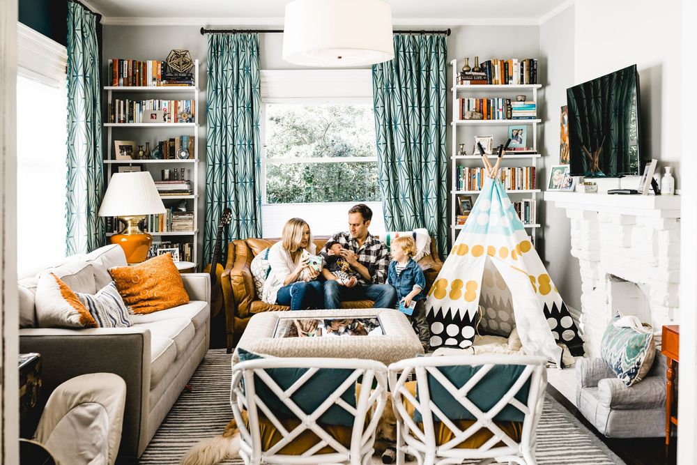 Cozy living room interior with teal curtains, built-in bookshelves, and comfortable seating arrangement.