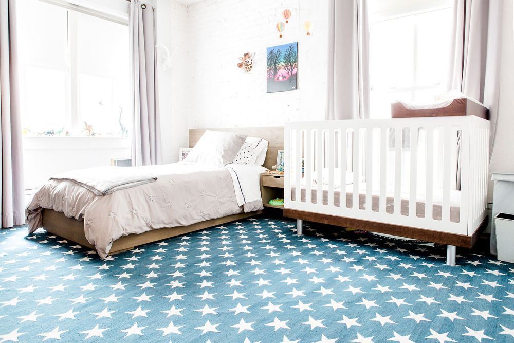 Bright nursery room with white crib and blue star-patterned rug creating a peaceful sleeping space.
