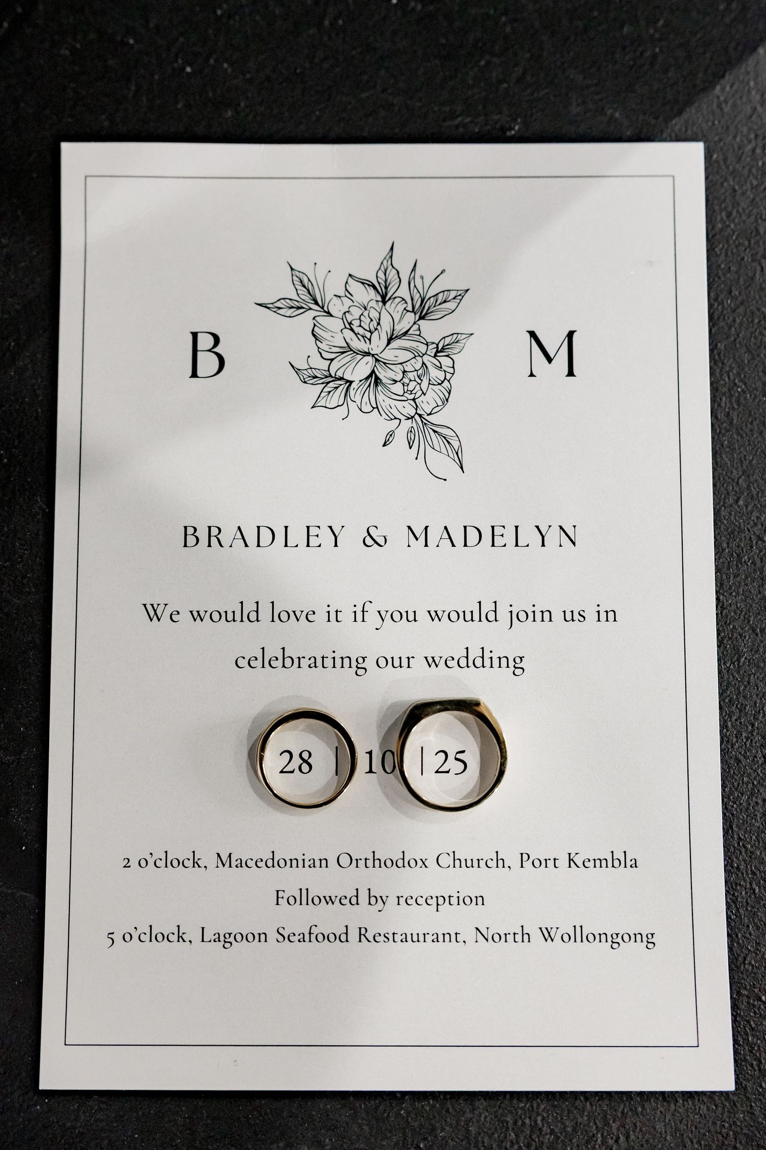 Wedding invitation details and rings displayed artistically with floral design elements and elegant typography.
