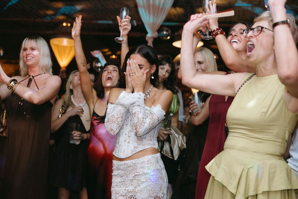 Guests dancing and celebrating at a lively wedding reception with colorful lighting.