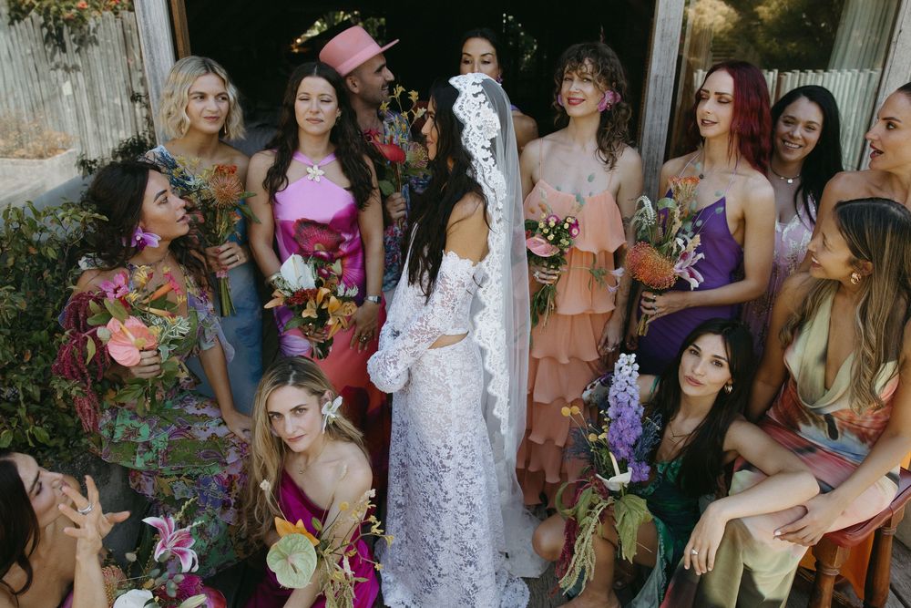 A group of people gather outdoors in formal attire for a wedding celebration with floral decorations.