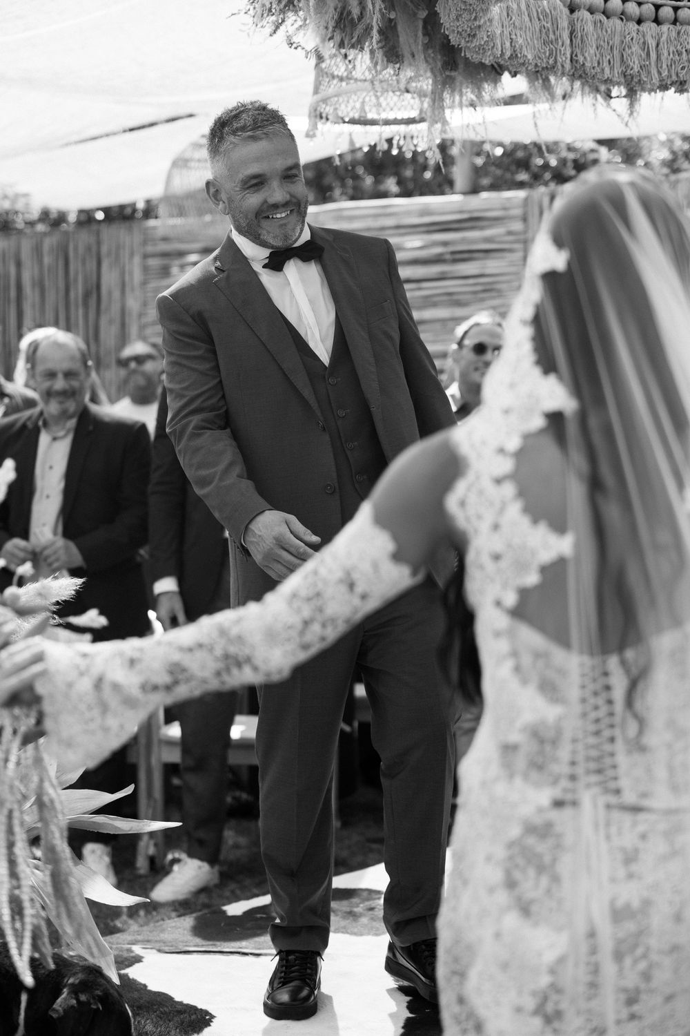 Black and white photo capturing a joyful moment during outdoor wedding ceremony.