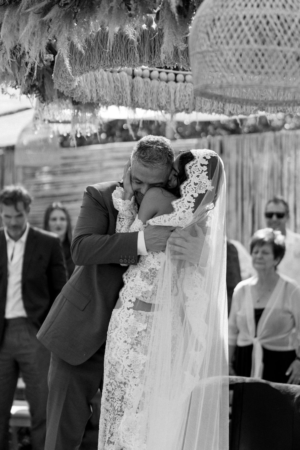 Black and white wedding ceremony photo showing couple sharing intimate moment under lace veil.