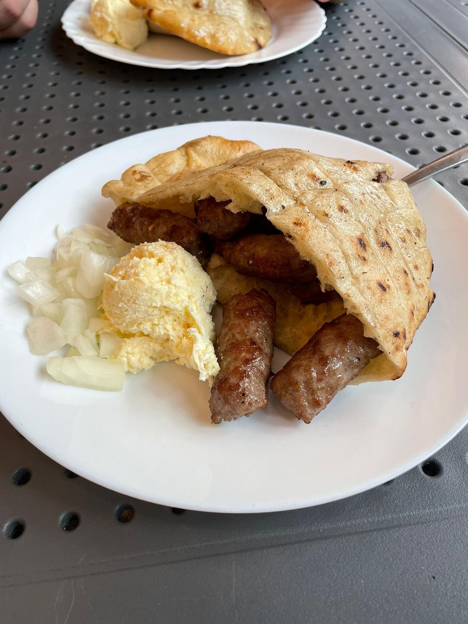 Breakfast plate with scrambled eggs and sausage links served with buttery toast on a white ceramic dish.