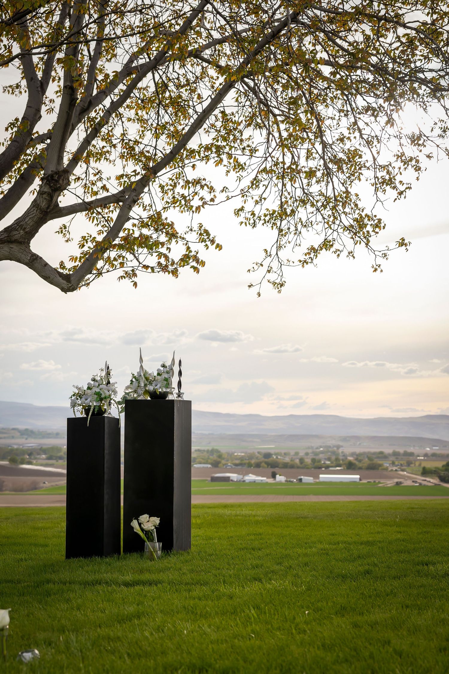 Black and white wedding decor. White floral arrangement on black pillars outdoor venue, Garman Hill Wilder Idaho