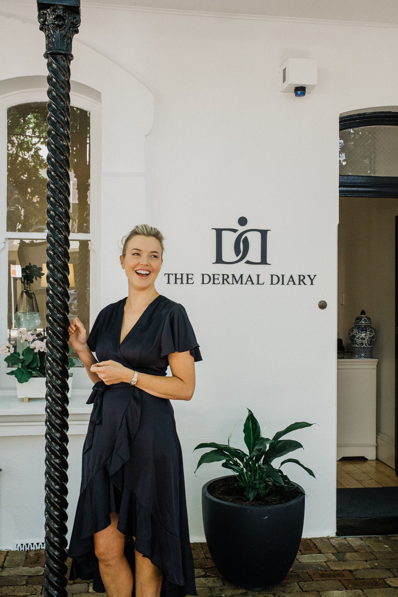 Professional spa entrance with black planters and white columns featuring The Dermal Diary signage.