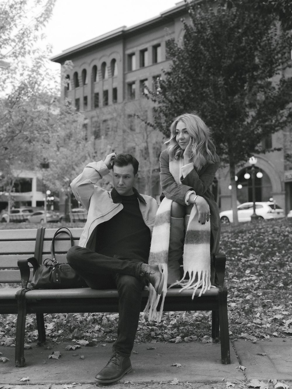 A person sits alone on a park bench in a moody black and white photo series showing different resting positions.