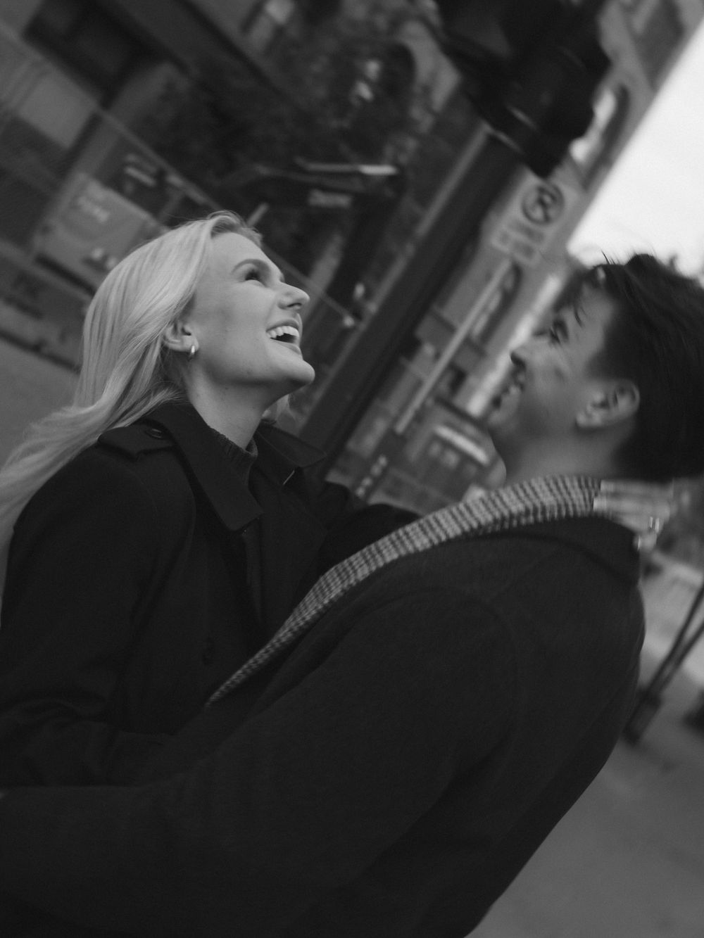 Black and white candid photo of a couple laughing together on a city street.