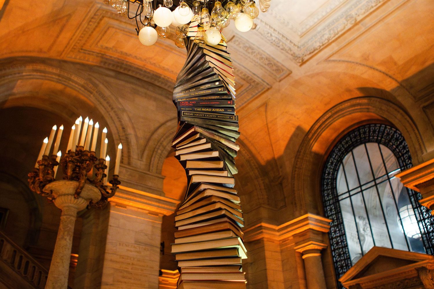 Ornate library interior with spiral staircase and dramatic arched ceiling illuminated by warm lighting.