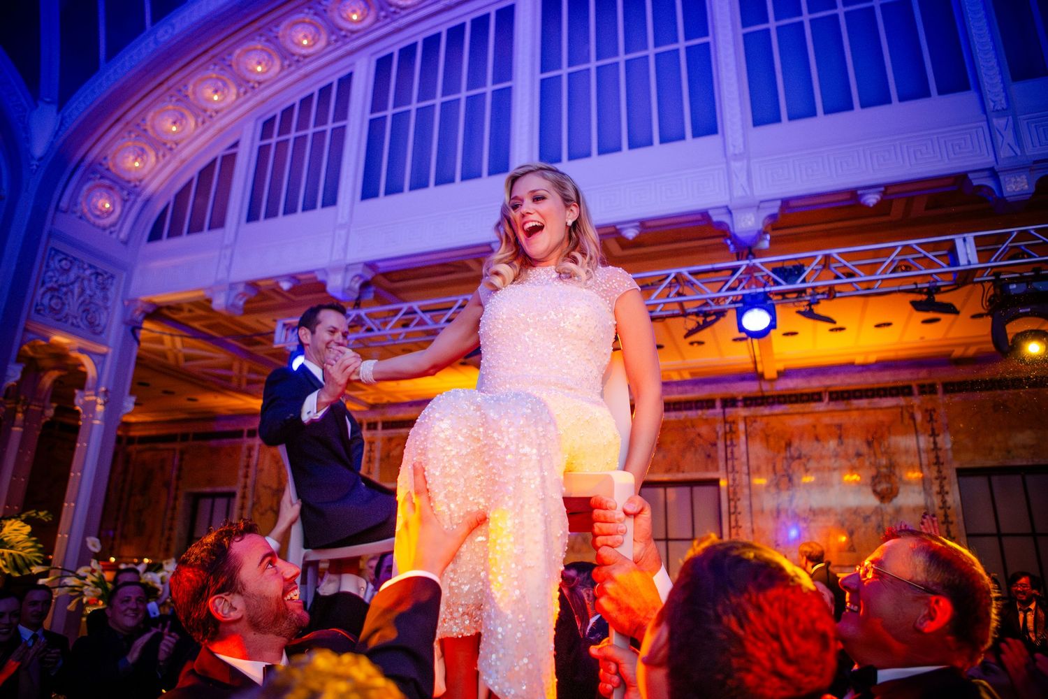Wedding couple shares their first dance under warm lighting in an ornate ballroom venue during their reception celebration.