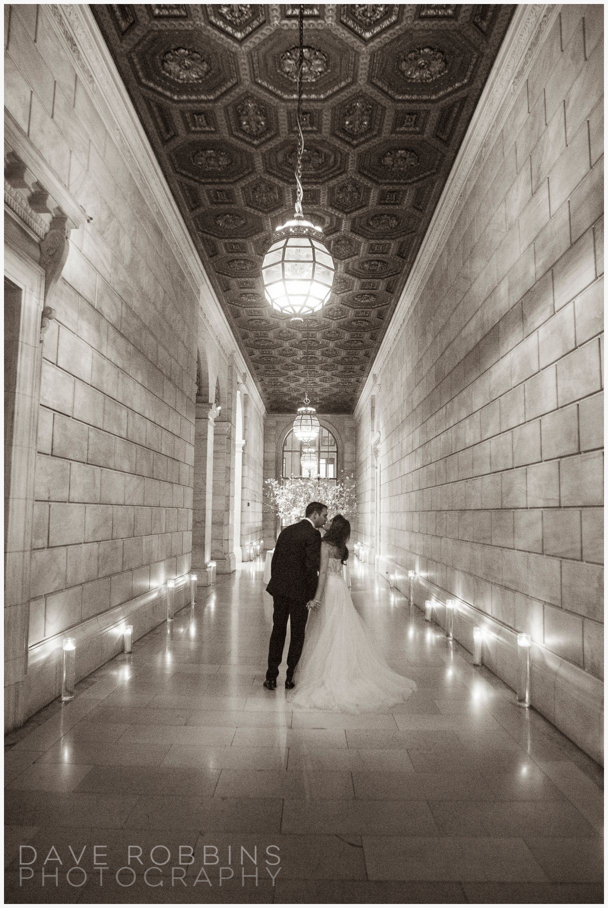 Black and white photo sequence showing two figures walking through an ornate marble hallway with dramatic lighting and patterned ceiling.
