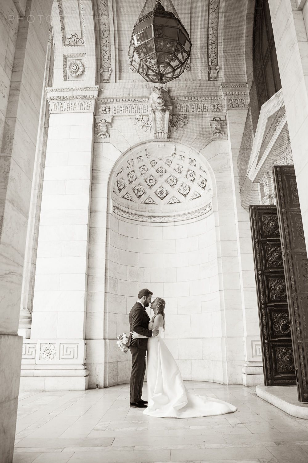 A romantic black and white wedding photo series showing a couple in an elegant architectural setting with ornate columns.