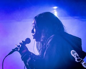 in purple light singer performs with microphone.