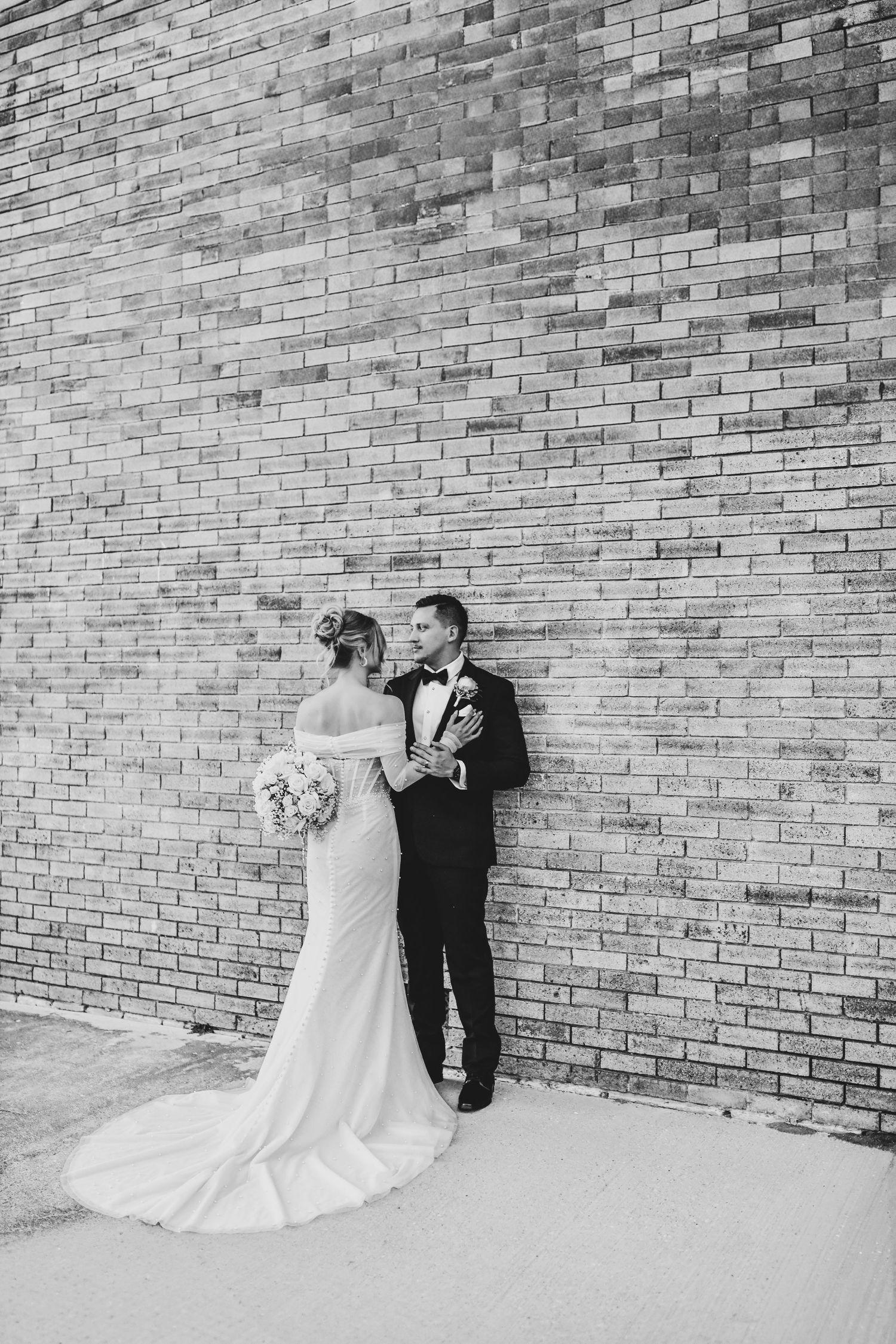 Bride and groom sharing a tender forehead kiss in front of industrial textures and neon alley lights in Deep Ellum