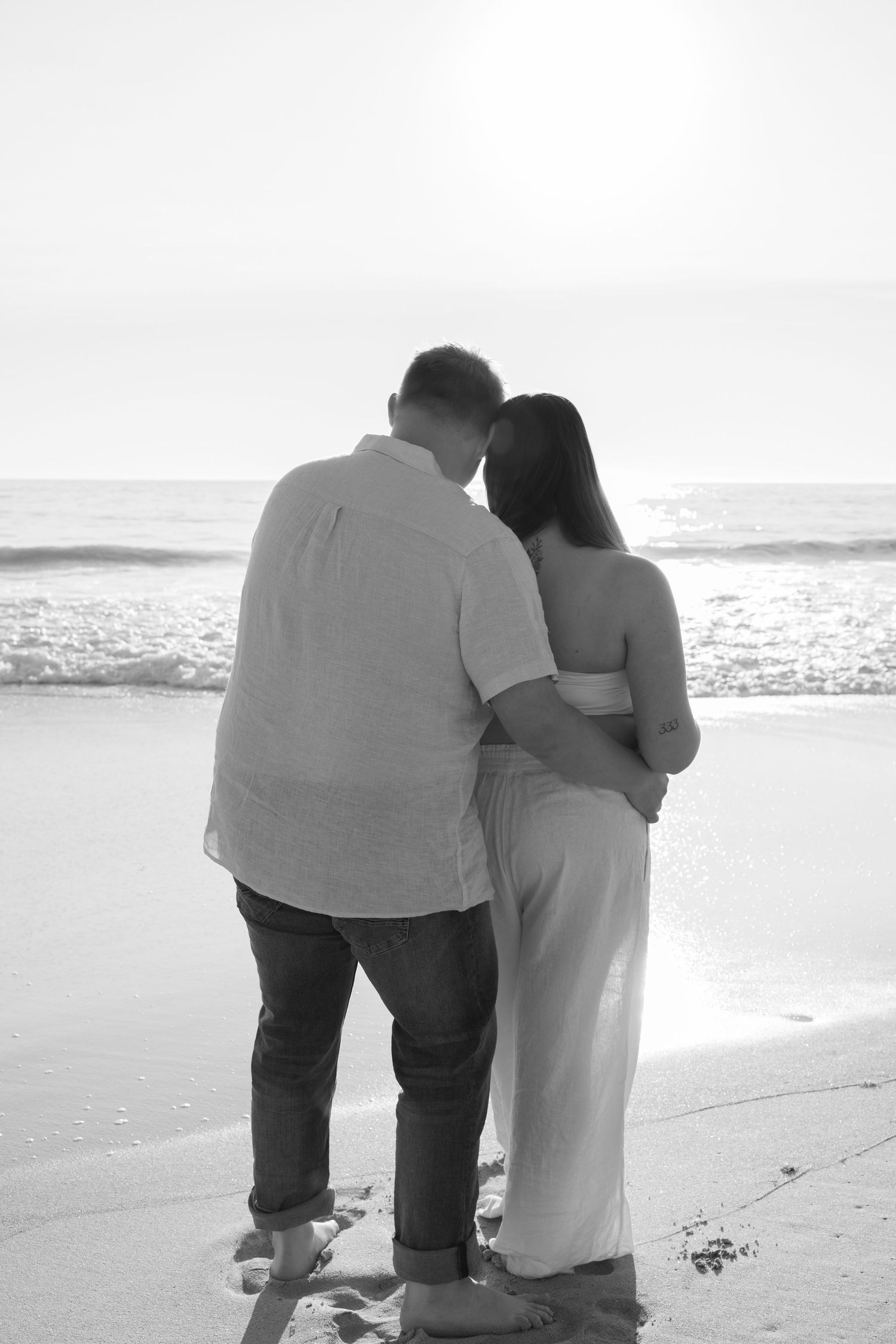 A series of black and white photos showing a couple walking together on a beach at sunset.