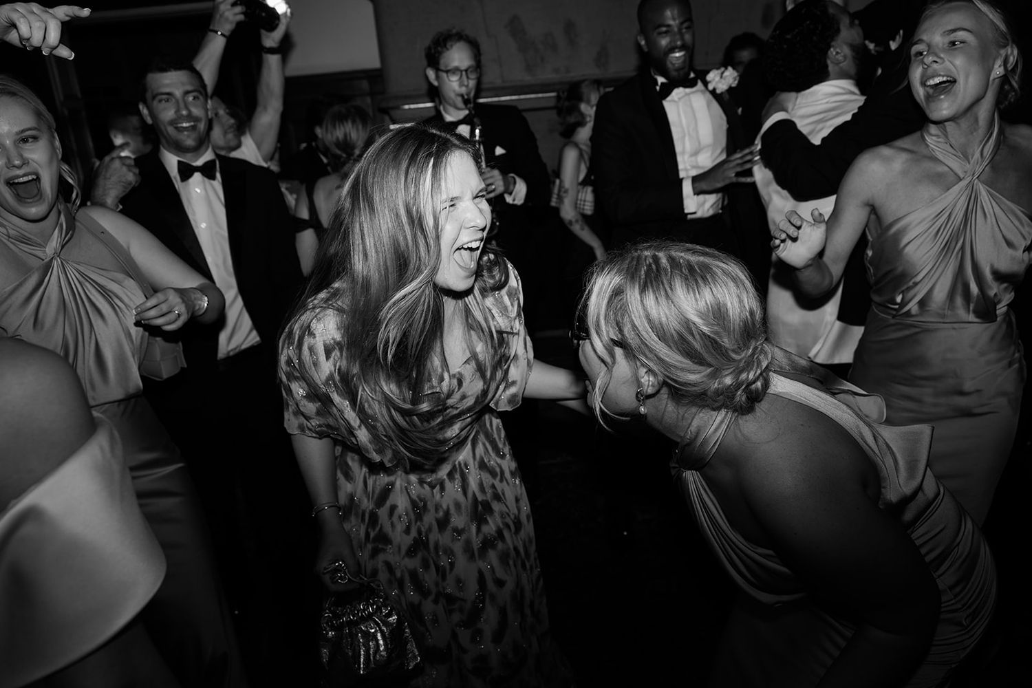 A black and white photo shows people laughing and enjoying themselves at what appears to be a social gathering.