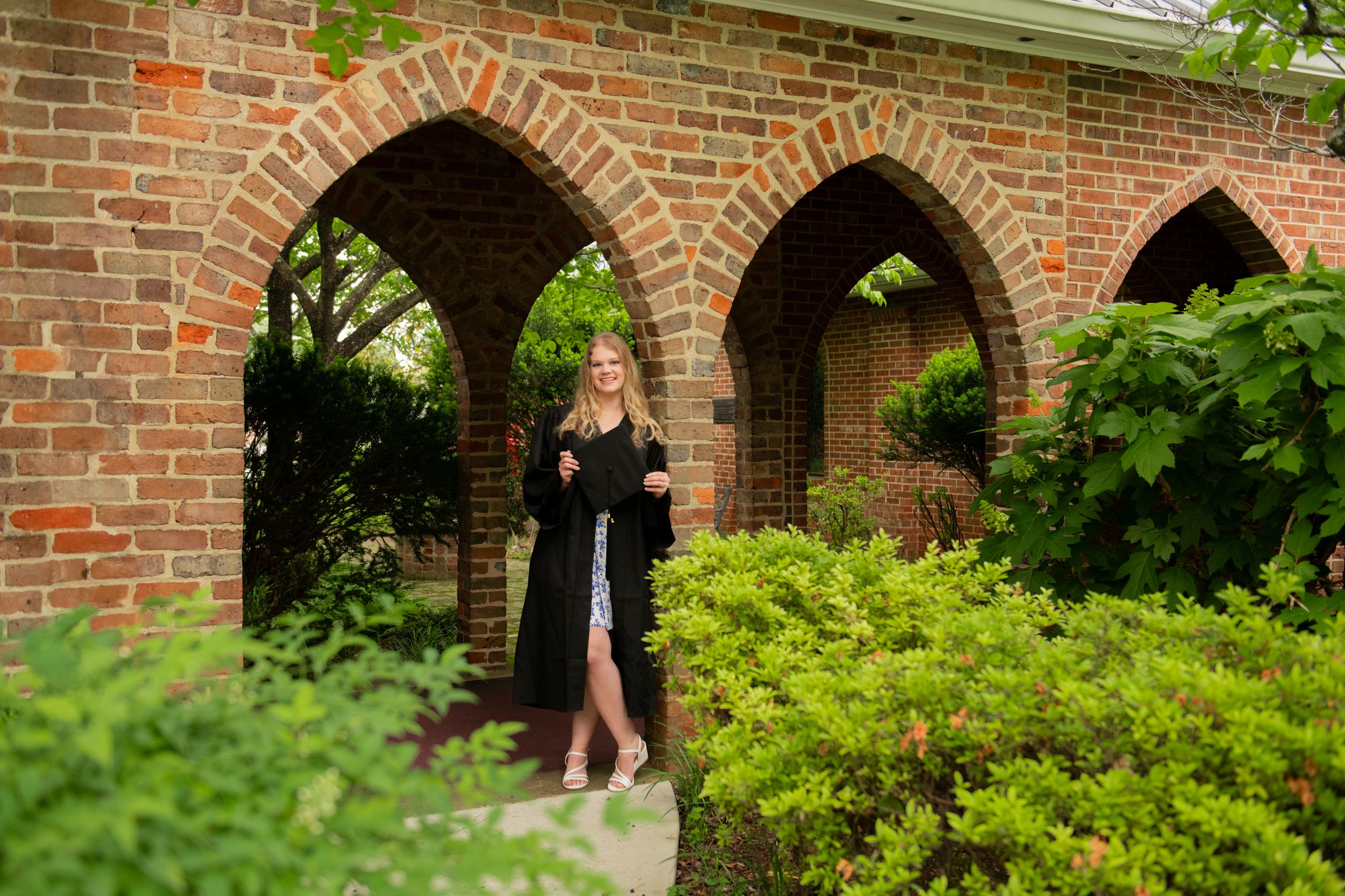 Gothic-style brick archways with green foliage visible in an outdoor architectural setting.
