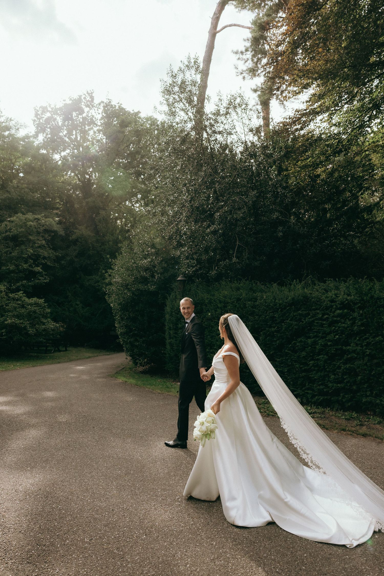 A couple poses for romantic wedding portraits on a garden path at sunset.