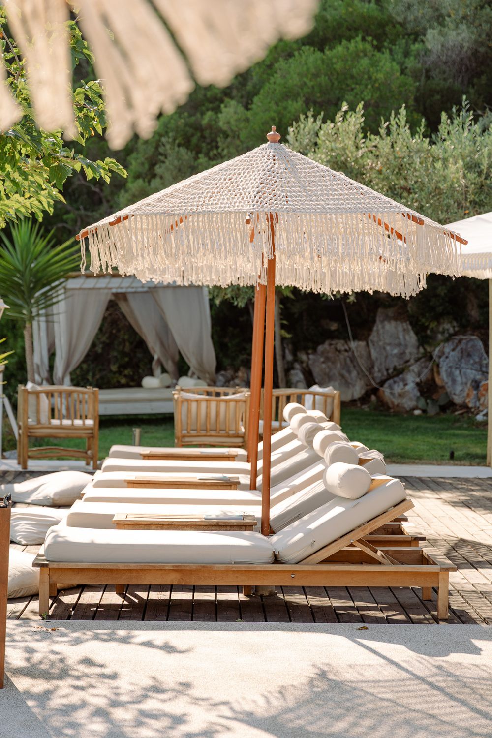 Wooden walkway leading to shaded sunbeds in a minimal beach setting.