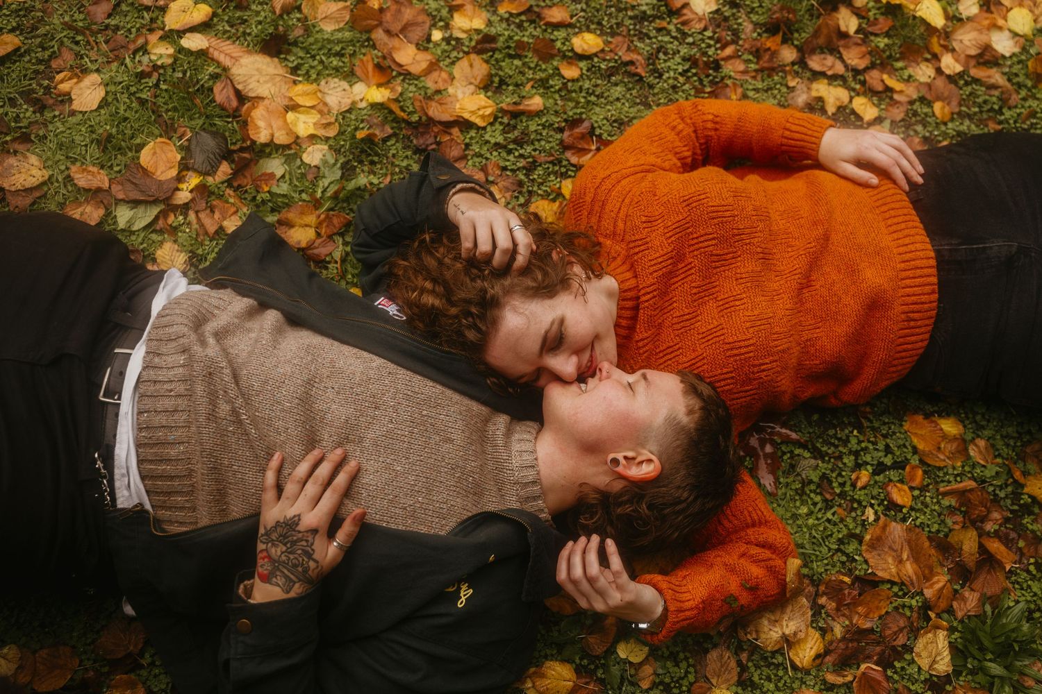 Person in orange sweater and brown beanie lies on autumn leaves in a playful sequence of photos.
