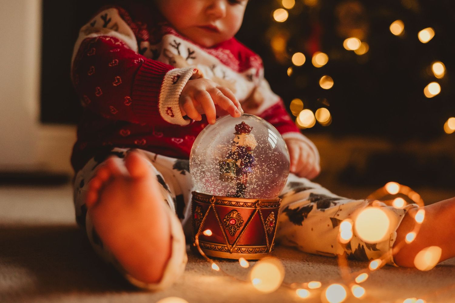 A snow globe and string lights create a cozy holiday atmosphere in dim lighting.