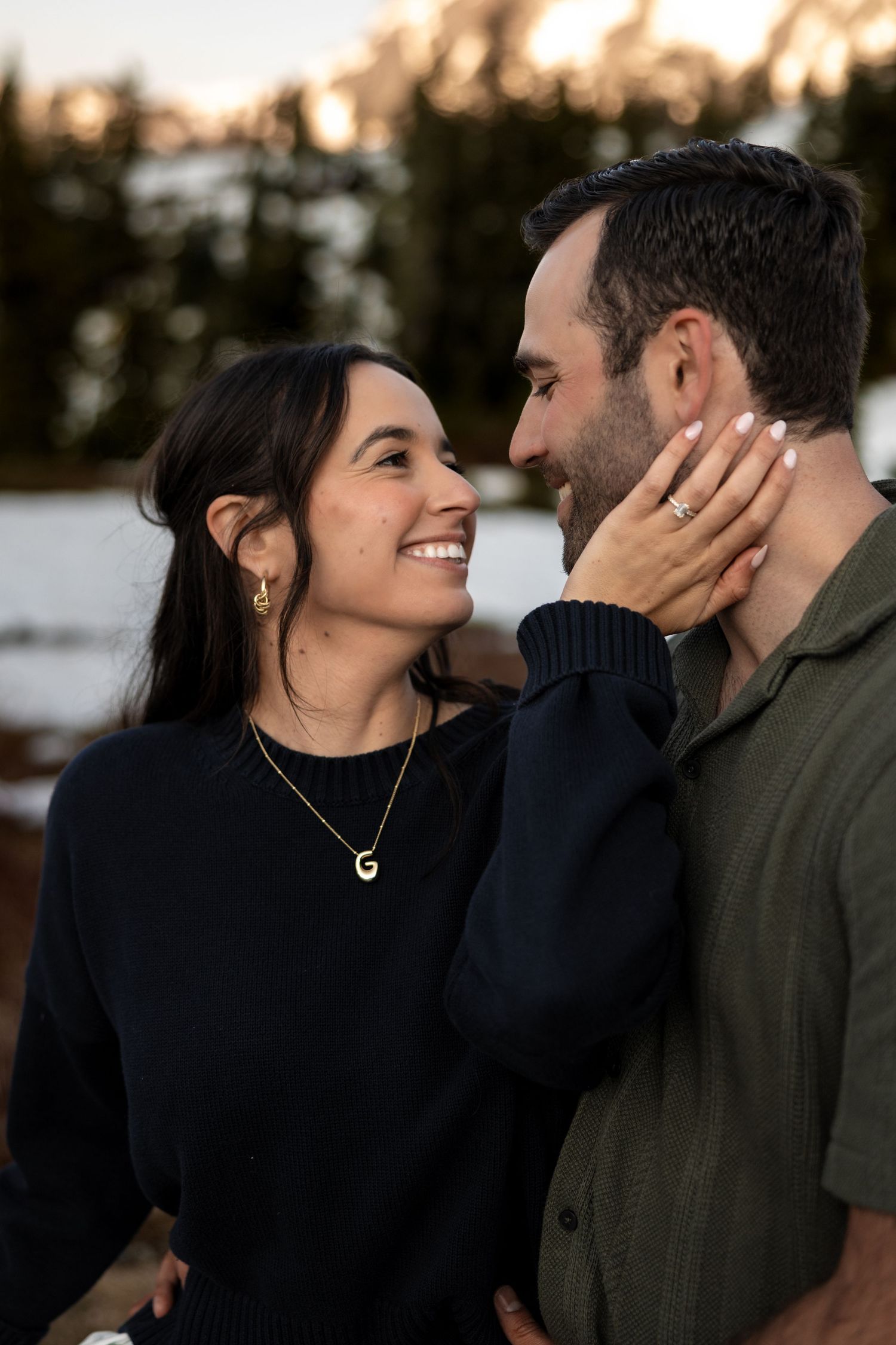 A romantic couple shares intimate moments against a moody sunset backdrop in winter.