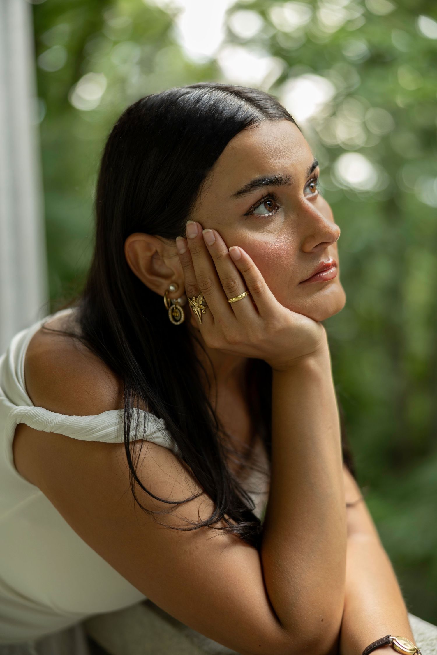 A series of artistic profile portraits showing contemplative poses with dark hair against a blurred green background.