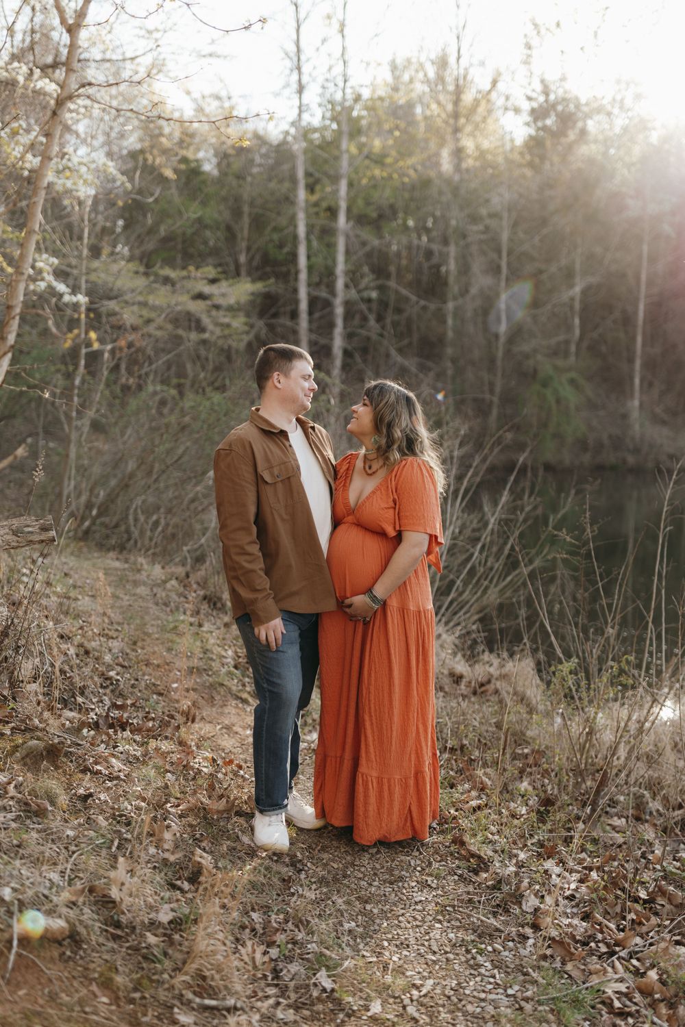 Couple stands on woodland path during golden hour photography session. Virginia/ North Carolina Maternity Session