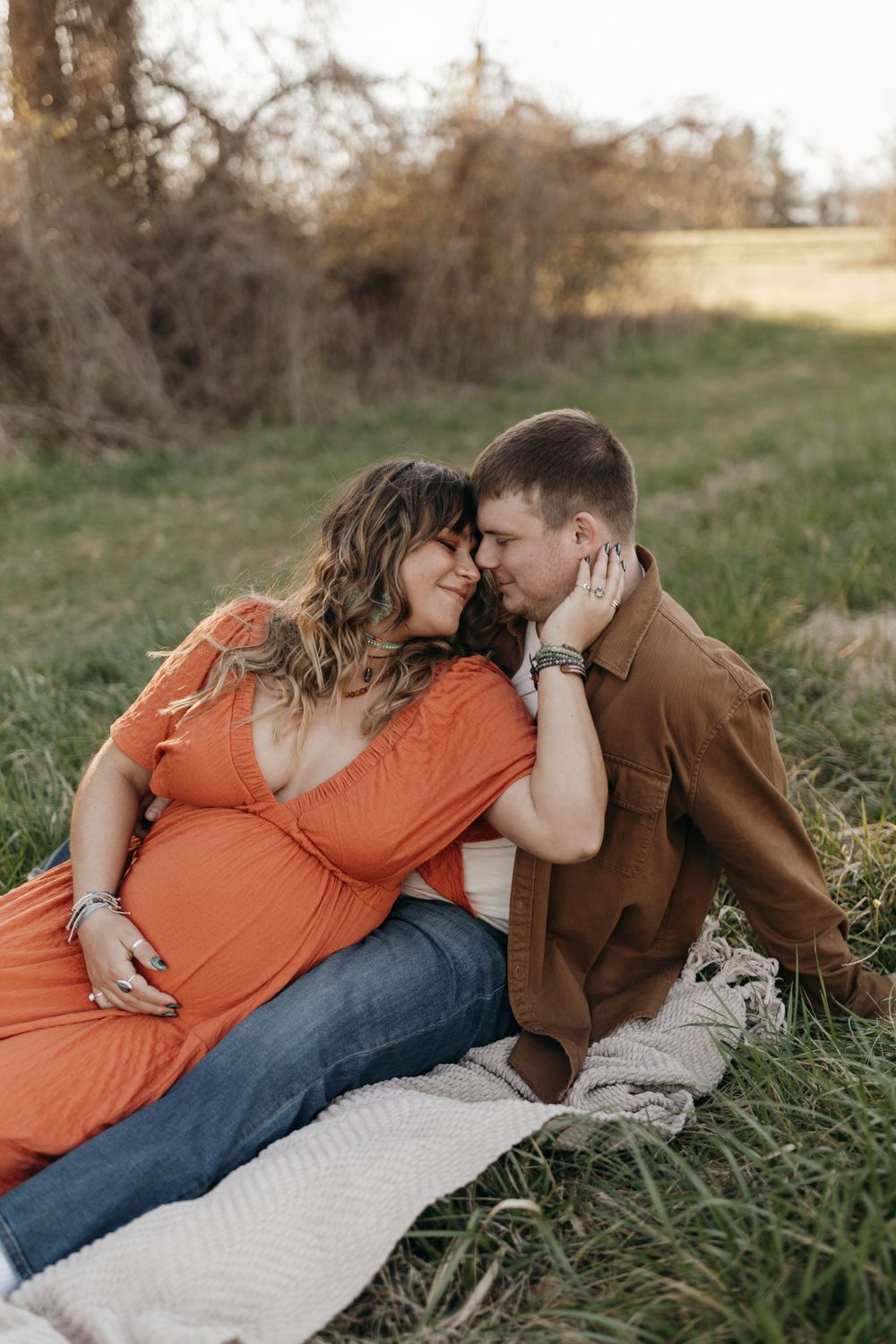 Intimate maternity photo of couple relaxing on blanket in grassy field at sunset. Virginia/ North Carolina Maternity Session