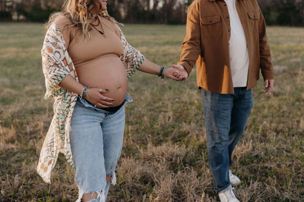 Intimate maternity photoshoot in a grassy field with warm sunset lighting. Virginia/ North Carolina Maternity Session