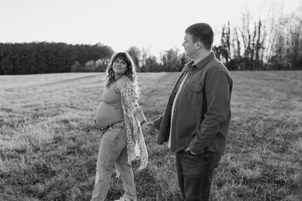 Black and white maternity photo of couple standing in an open field. Virginia/ North Carolina Maternity Session