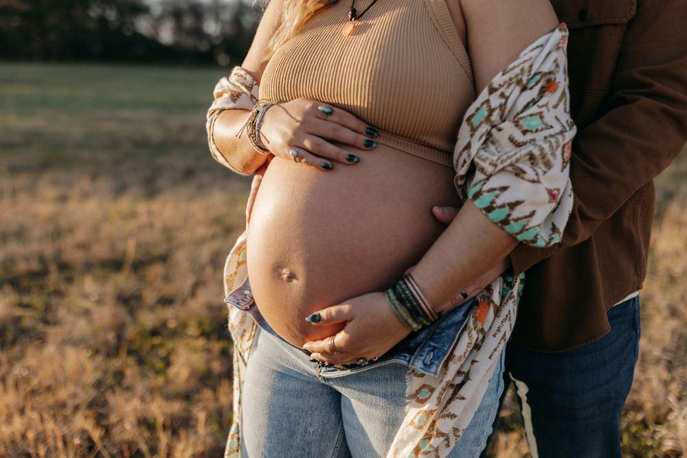 Close-up shot of pregnant belly with hands tenderly placed during outdoor photoshoot. Virginia/ North Carolina Maternity Session