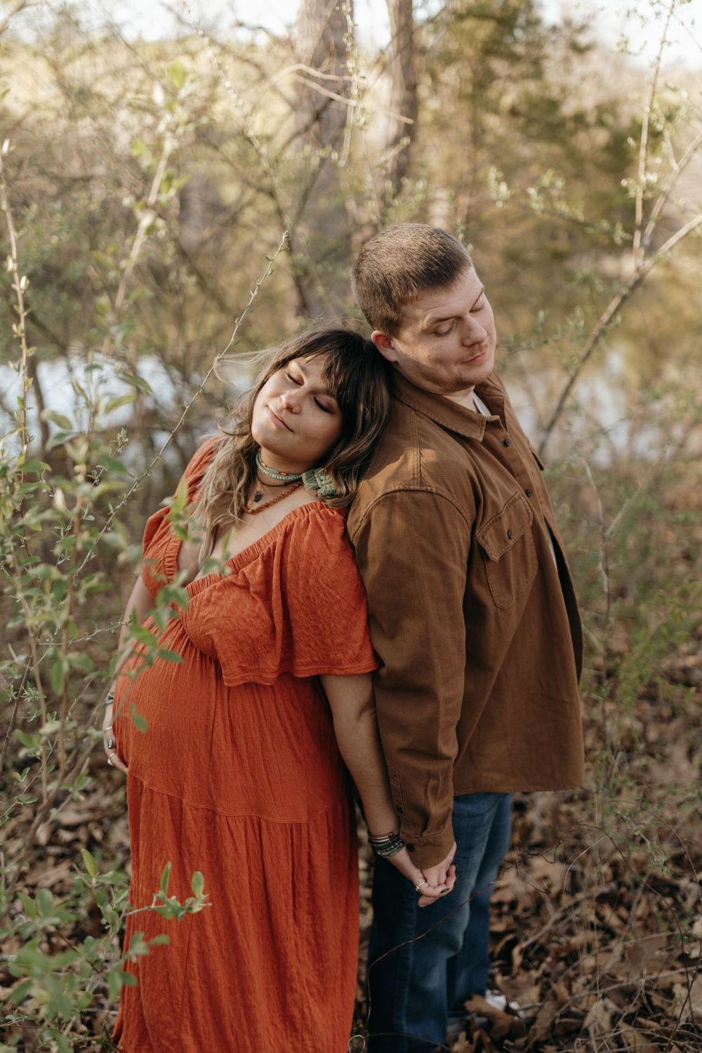 Couple in coordinating autumn colors share playful moment during maternity photoshoot in nature. Virginia/ North Carolina Maternity Session