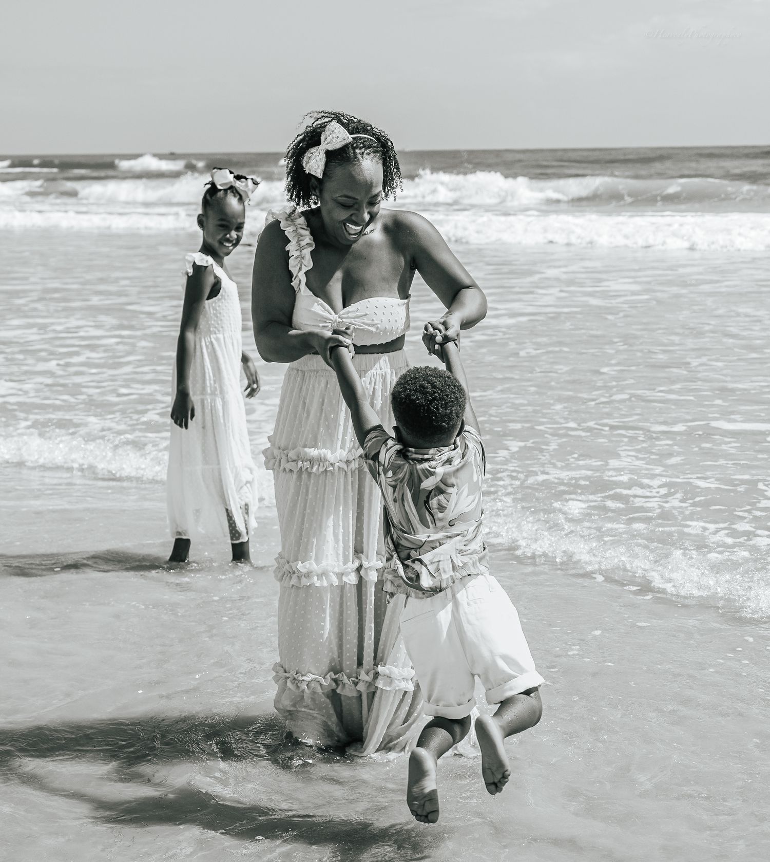 Family playing and splashing together at the beach in black and white.