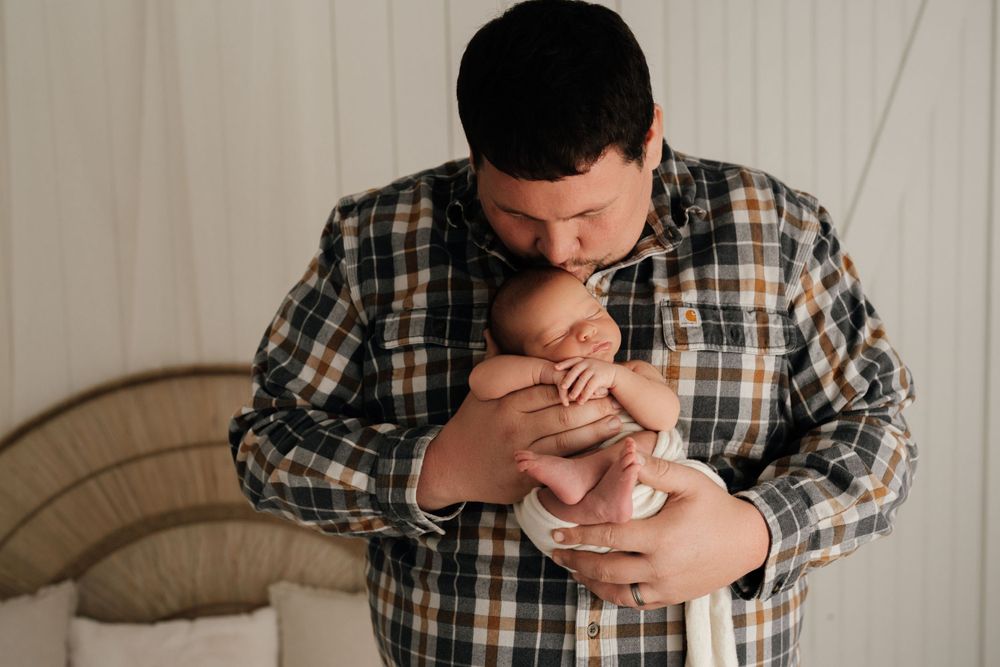 Tender moment between parent and newborn during lifestyle photography session.