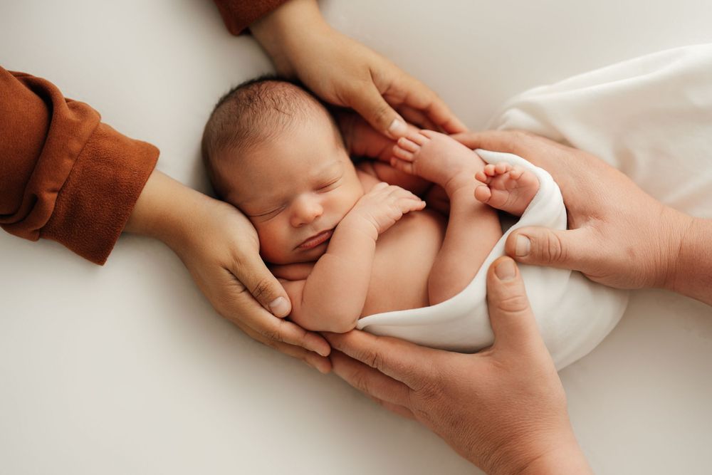 Newborn baby receiving gentle care during newborn photo shoot..