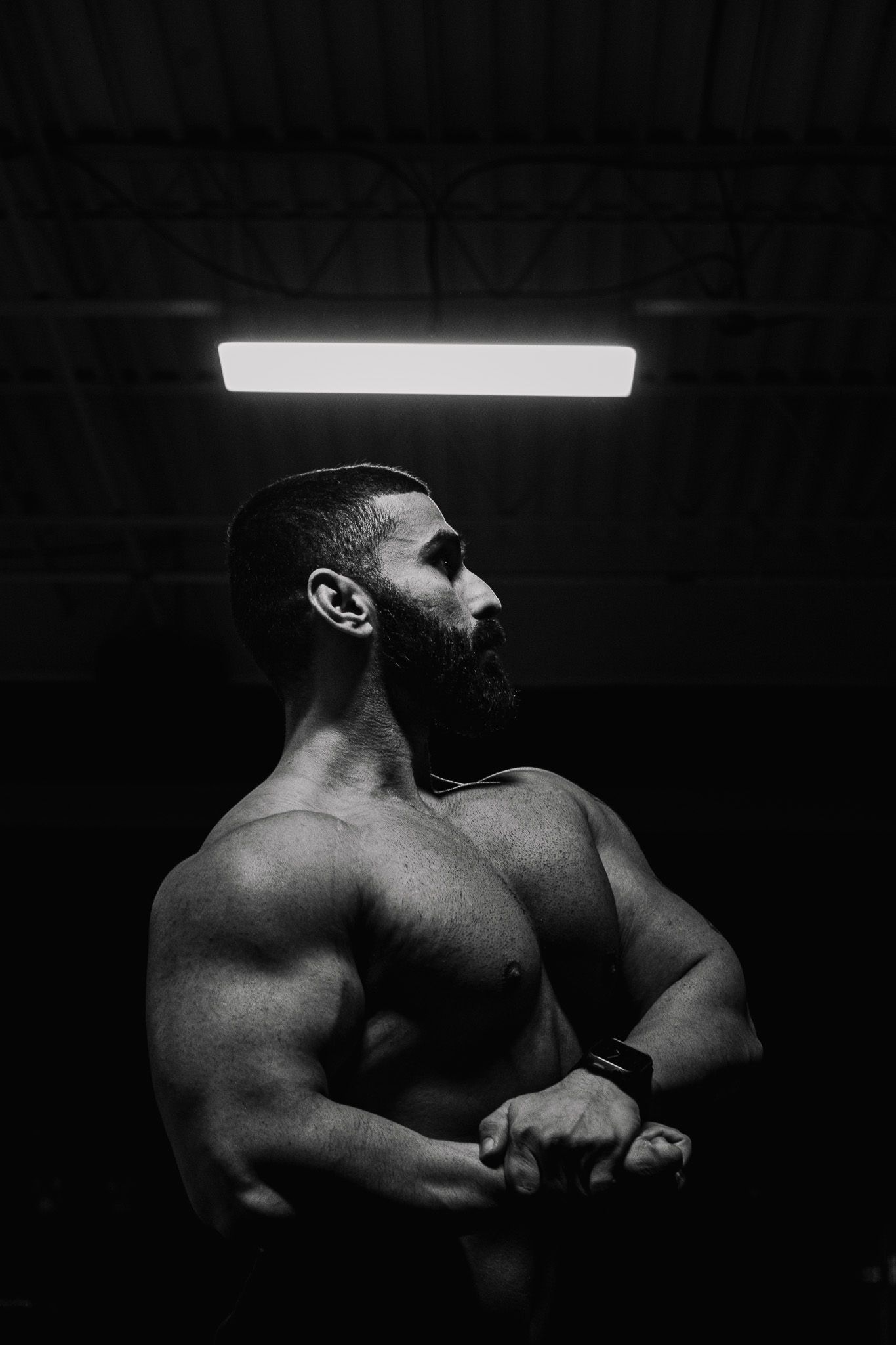 Male athlete lifting weights in high-contrast gym lighting