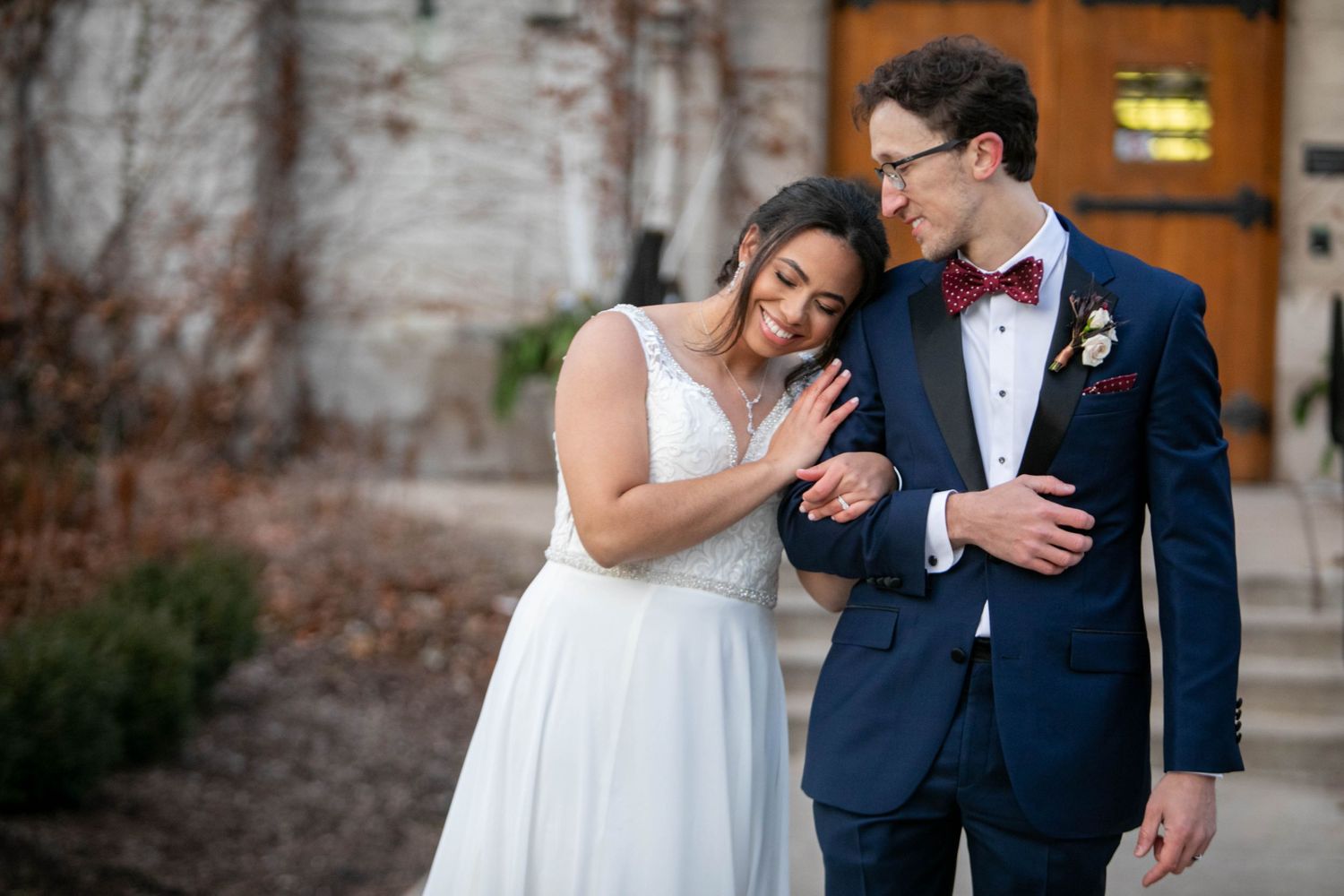 Happy couple in wedding attire share joyful moment together outdoors, with bride in white dress and groom in navy suit.