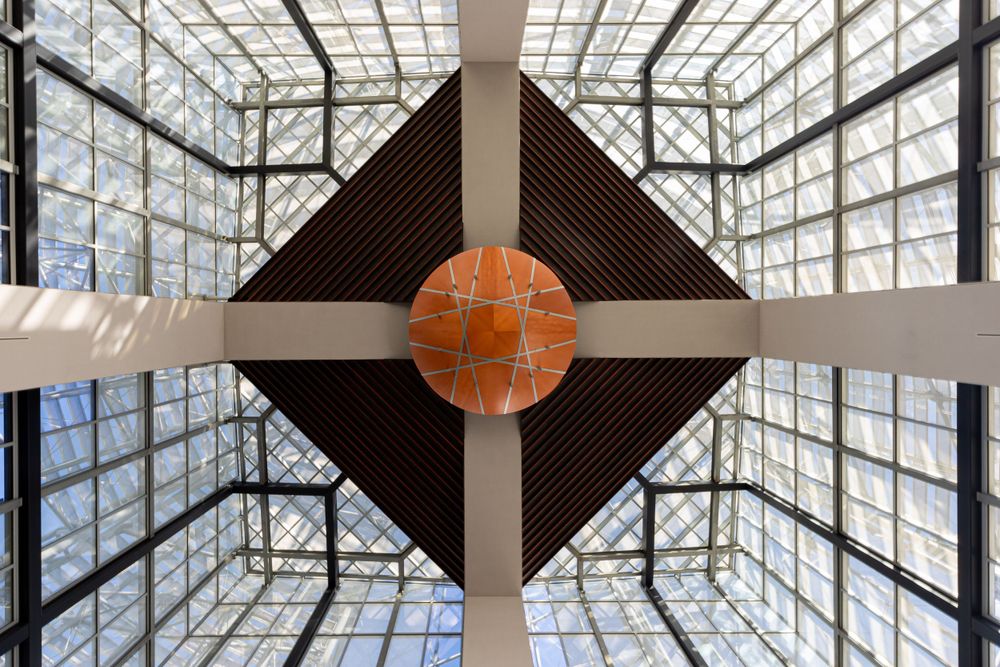 Modern architectural interior with geometric glass ceiling and orange spherical centerpiece in the San Diego Public Library.