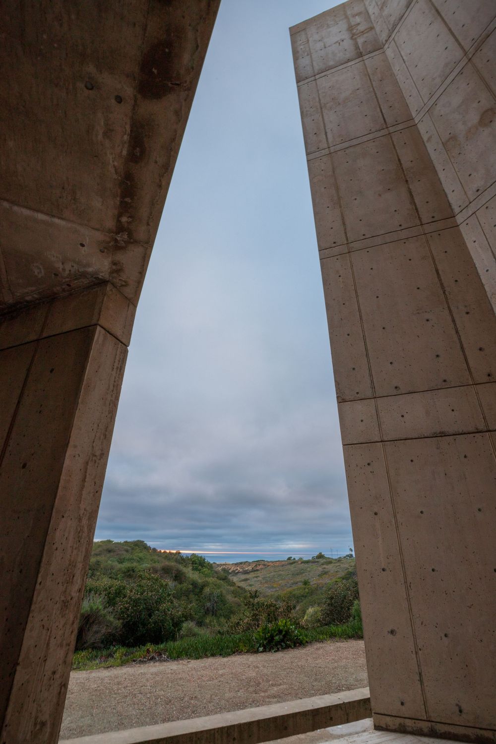 View of cloudy coastal landscape framed through concrete architectural elements at the Salk Institute in San Diego, California.